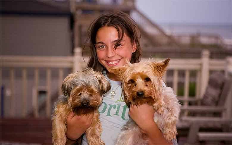 une jeune fille porte 2 chiens dans ses bras