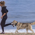 un husky courant sur la plage avec sa maîtresse